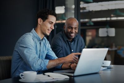 Zwei Menschen sitzen vor einem Laptop und beraten