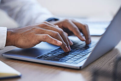 Ein Mann tippt auf der Laptop Tastatur