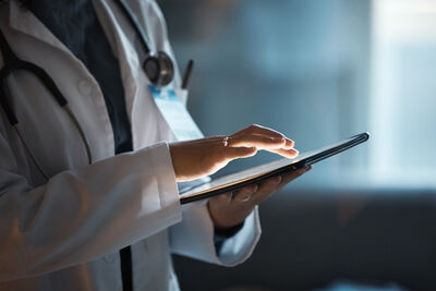 Risikovorsorge in der Gesundheits-IT Mensch im Arztkittel hält Tablett in der Hand