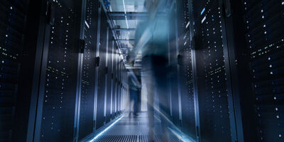 Aufnahme eines Korridors in einem gro&szlig;en Rechenzentrum voller sich bewegender und arbeitender Menschen.